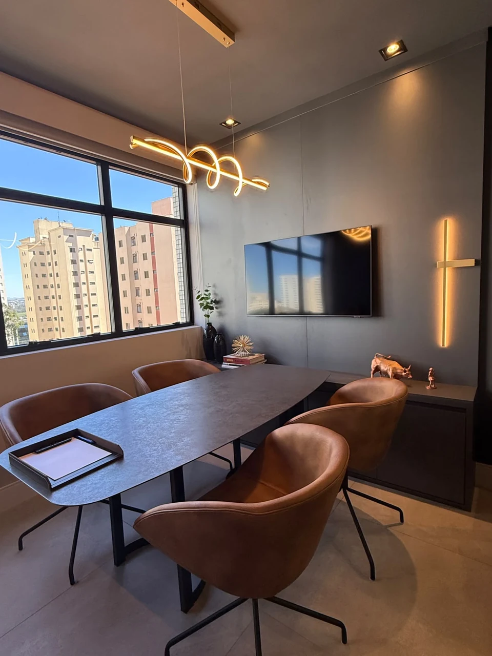 Sala de reunião da Ikedo Advisory, com mesa cinza, poltronas marrons e iluminação natural